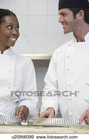 Two chefs preparing food in kitchen smiling View Large Photo Image Stock Photo - Two chefs preparing food in kitchen smiling. Fotosearch