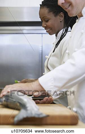 Picture - Two chefs preparing salmon in kitchen. Fotosearch