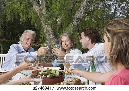 Two couples toasting at garden table View Large Photo Image Stock Photo - Two couples toasting at garden table. Fotosearch