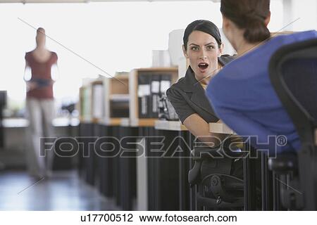 Two female business colleagues talking in office View Large Photo Image Stock Image - Two female business colleagues talking in office. Fotosearch