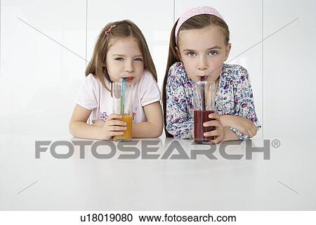 Two girls (7-9) sitting at table with orange and chocolate drinks portrait View Large Photo Image Stock Image - Two girls (7-9) sitting at table with orange and chocolate drinks portrait. Fotosearch
