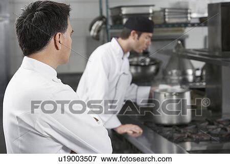 Two male chefs working in kitchen View Large Photo Image Stock Photo - Two male chefs working in kitchen. Fotosearch