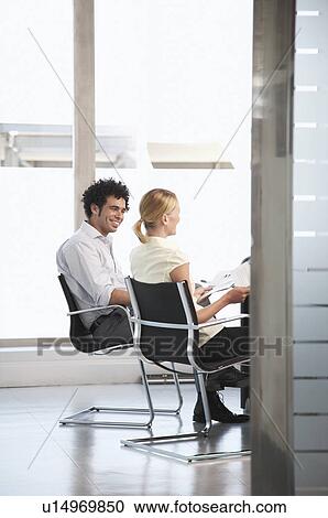 Two office workers sitting in conference room View Large Photo Image Stock Image - Two office workers sitting in conference room. Fotosearch