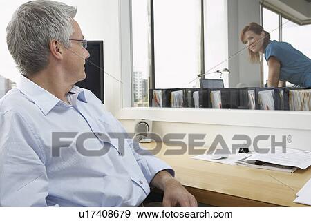 Two office workers smiling in office View Large Photo Image Stock Photo - Two office workers smiling in office. Fotosearch