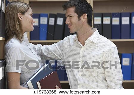 Two office workers standing in file storage room side view View Large Photo Image Stock Photo - Two office workers standing in file storage room side view. Fotosearch
