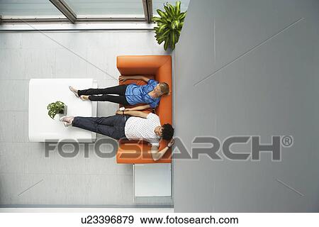 Two people reclining on couch in reception room view from above View Large Photo Image Stock Photo - Two people reclining on couch in reception room view from above. Fotosearch