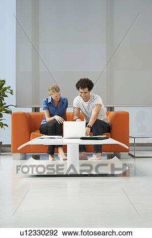 Two people using laptop in reception room View Large Photo Image Stock Image - Two people using laptop in reception room. Fotosearch
