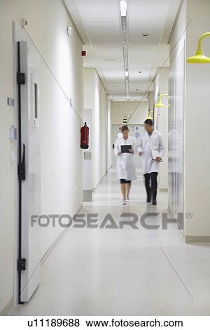 Two scientists walking down hallway View Large Photo Image Stock Photo - Two scientists walking down hallway. Fotosearch