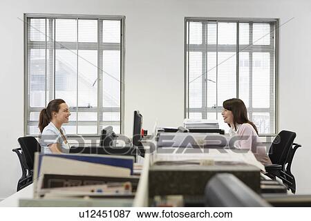 Two women at desks in office side view View Large Photo Image Stock Photo - Two women at desks in office side view. Fotosearch