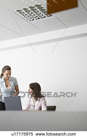Stock Photography - Two women discussing in office. Fotosearch