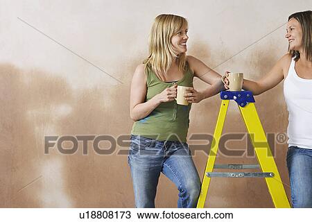 Two women leaning on step ladder holding mugs View Large Photo Image Stock Image - Two women leaning on step ladder holding mugs. Fotosearch