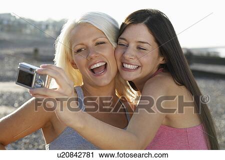 Two women photographing themselves on beach smiling portrait View Large Photo Image Stock Image - Two women photographing themselves on beach smiling portrait. Fotosearch