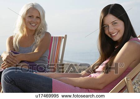Stock Photography - Two women sitting on deckchairs on beach portrait. Fotosearch