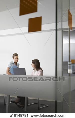 Two women talking in office seen through glass View Large Photo Image Stock Image - Two women talking in office seen through glass. Fotosearch
