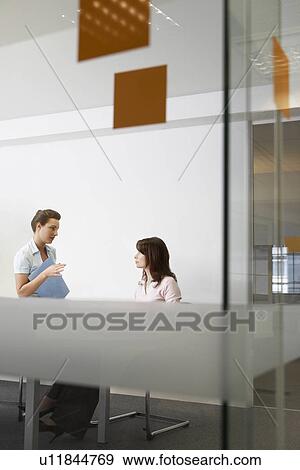 Two women talking in office seen through glass View Large Photo Image Stock Photo - Two women talking in office seen through glass. Fotosearch