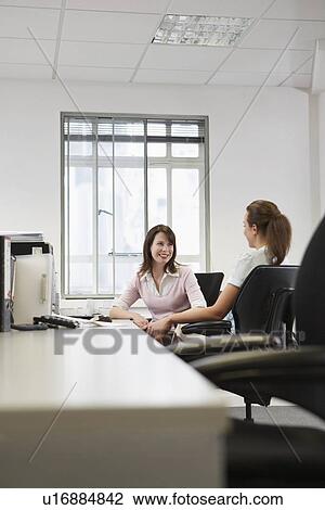 Two women talking in office View Large Photo Image Stock Image - Two women talking in office. Fotosearch