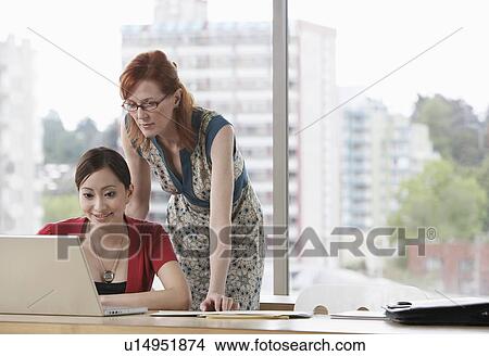Two women using laptop in office View Large Photo Image Picture - Two women using laptop in office. Fotosearch