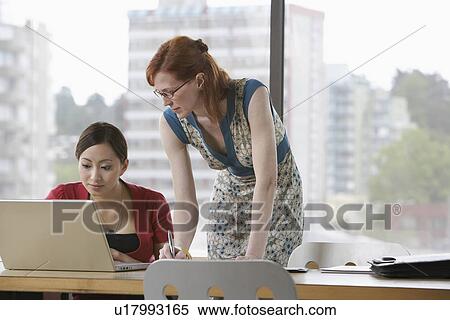 Two women using laptop in office View Large Photo Image Stock Photography - Two women using laptop in office. Fotosearch