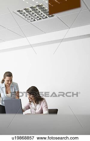 Two women with laptop in office View Large Photo Image Stock Photo - Two women with laptop in office. Fotosearch