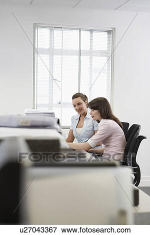 Two women working at desk in office side view View Large Photo Image Stock Photo - Two women working at desk in office side view. Fotosearch