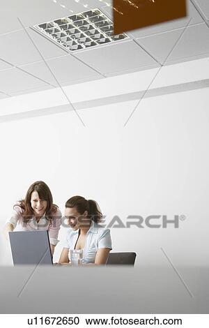 Two women working on laptop in office View Large Photo Image Stock Image - Two women working on laptop in office. Fotosearch