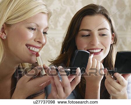 Two young women putting on make up close up View Large Photo Image Stock Photo - Two young women putting on make up close up. Fotosearch