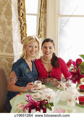 Two young women sitting at dining table portrait elevated view View Large Photo Image Picture - Two young women sitting at dining table portrait elevated view. Fotosearch