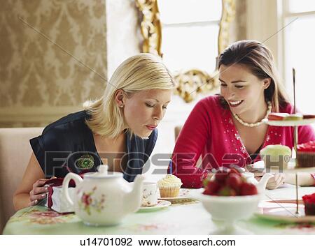 Two young women sitting at dining table View Large Photo Image Stock Image - Two young women sitting at dining table. Fotosearch