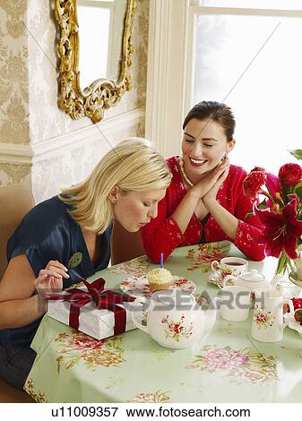 Stock Photo - Two young women sitting at dining table elevated view. Fotosearch