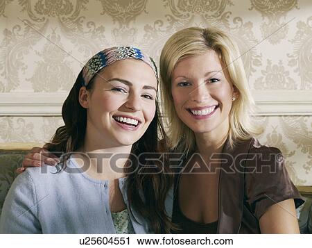 Two young women sitting on sofa portrait View Large Photo Image Stock Image - Two young women sitting on sofa portrait. Fotosearch