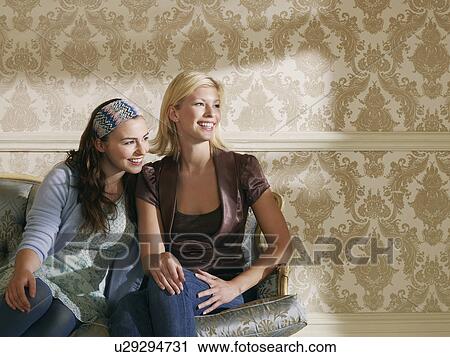 Two young women sitting on sofa View Large Photo Image Stock Image - Two young women sitting on sofa. Fotosearch