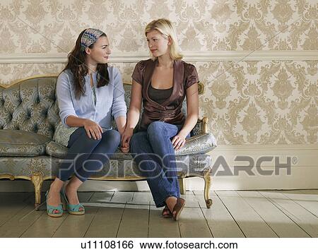 Two young women sitting on sofa View Large Photo Image Stock Photograph - Two young women sitting on sofa. Fotosearch