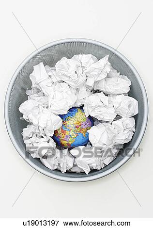 Stock Photo - Waste bin with globe among crumpled papers view from above. Fotosearch