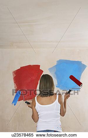 Woman facing wall painted on ble and red holding with paint rollers back view View Large Photo Image Stock Photography - Woman facing wall painted on ble and red holding with paint rollers back view. Fotosearch