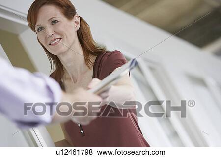 Stock Photo - Woman handing colleague document in office. Fotosearch