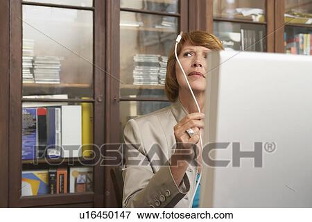 Woman holding and inspecting computer cable in living room View Large Photo Image Stock Photo - Woman holding and inspecting computer cable in living room. Fotosearch