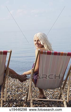 Woman holding man's hand sitting on deckchair on beach View Large Photo Image Stock Photo - Woman holding man's hand sitting on deckchair on beach. Fotosearch