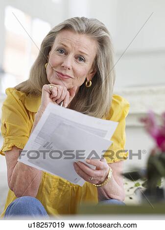 Woman holding paper documents sitting indoors portrait View Large Photo Image Stock Photo - Woman holding paper documents sitting indoors portrait. Fotosearch