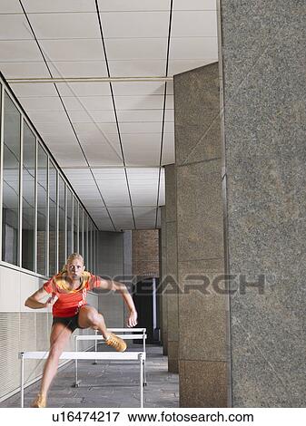 Woman jumping hurdles outside building View Large Photo Image Stock Photo - Woman jumping hurdles outside building. Fotosearch