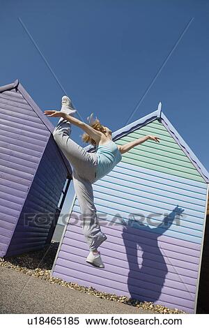 Stock Photography - Woman jumping in front of beach hut. Fotosearch