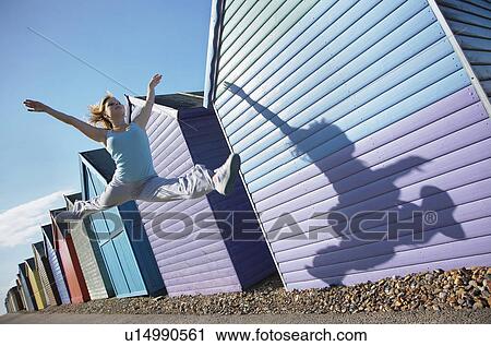Woman jumping in front of beach huts View Large Photo Image Stock Image - Woman jumping in front of beach huts. Fotosearch