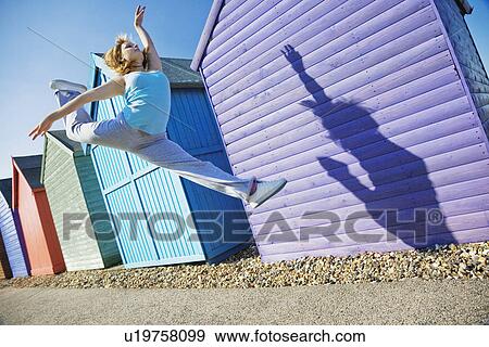 Woman jumping in front of beach huts View Large Photo Image Stock Photo - Woman jumping in front of beach huts. Fotosearch
