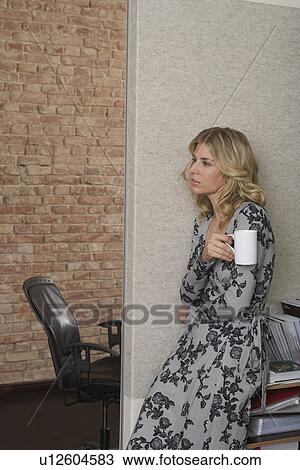 Woman leaning against bookcase with mug in office View Large Photo Image Stock Image - Woman leaning against bookcase with mug in office. Fotosearch