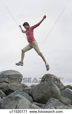 Woman leaping with arms raised over rocks View Large Photo Image Stock Image - Woman leaping with arms raised over rocks. Fotosearch