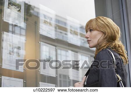 Woman looking in window outside estate agents View Large Photo Image Stock Photo - Woman looking in window outside estate agents. Fotosearch