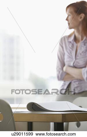 Woman looking out of window focus on desk in foreground View Large Photo Image Stock Photo - Woman looking out of window focus on desk in foreground. Fotosearch