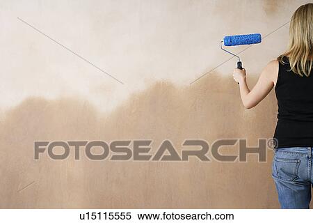 Stock Photography - Woman painting wall with paint roller back view. Fotosearch