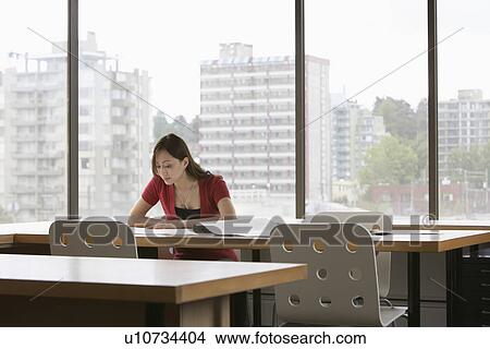 Woman reading at desk in office View Large Photo Image Picture - Woman reading at desk in office. Fotosearch