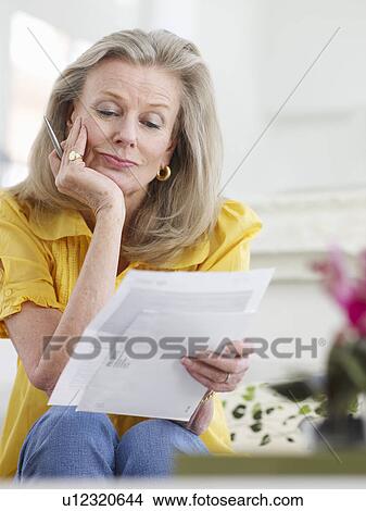 Woman reading paper documents indoors View Large Photo Image Picture - Woman reading paper documents indoors. Fotosearch