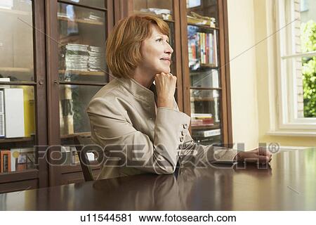 Woman sitting at table in living room View Large Photo Image Stock Image - Woman sitting at table in living room. Fotosearch